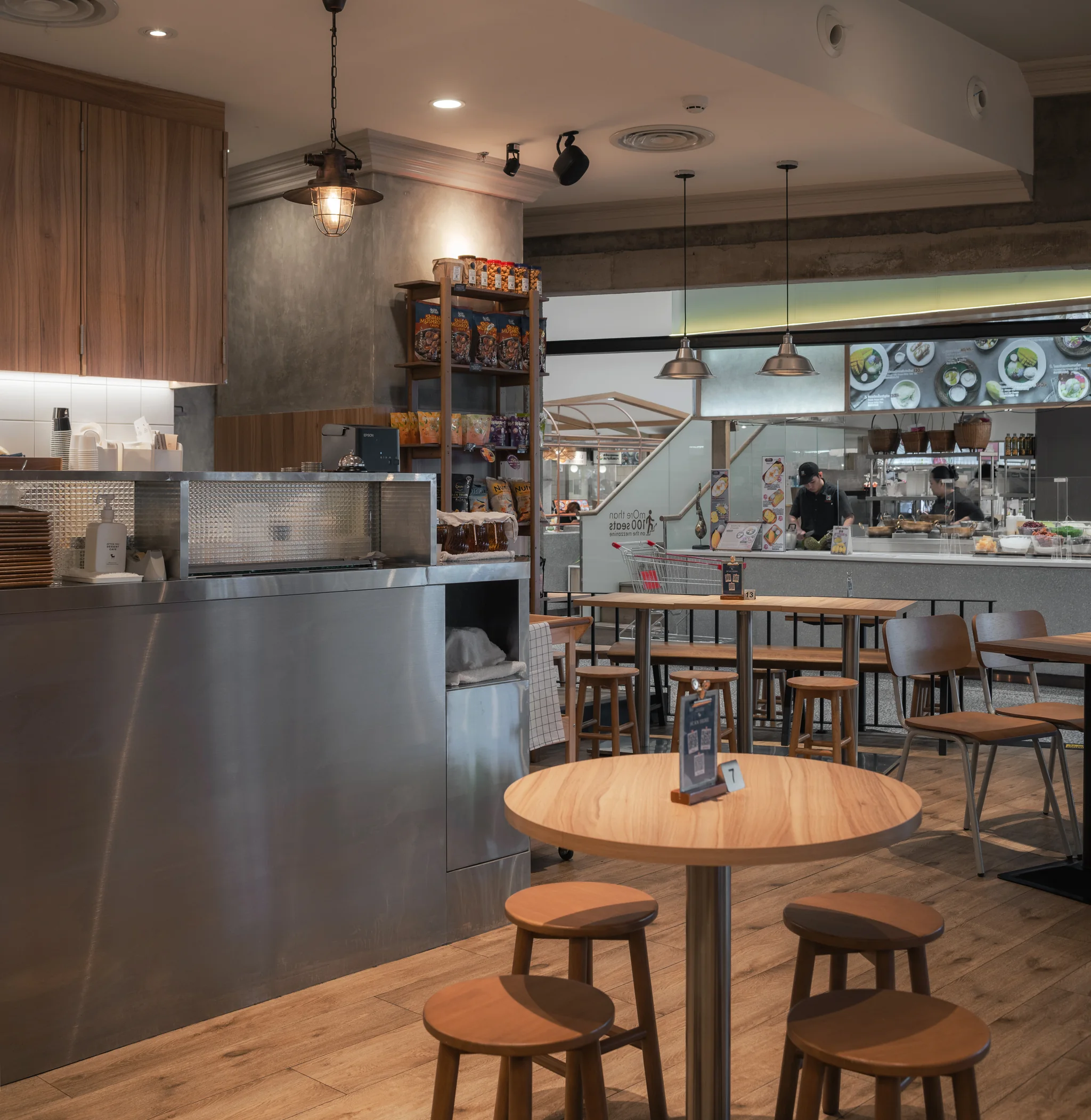 Round timber table beside the brushed-metal service counter and open kitchen.