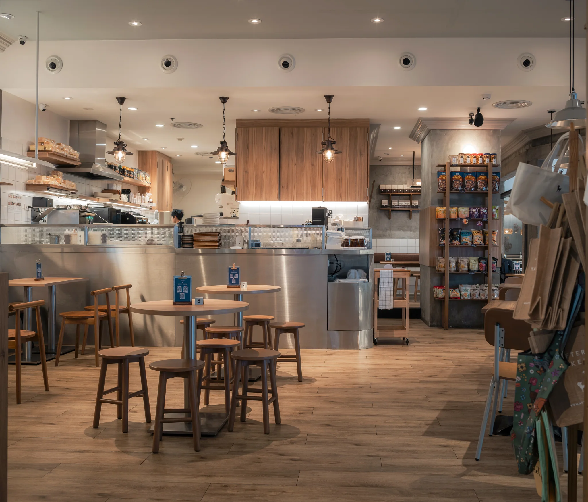Timber cafe tables and stools facing the preparation counter.