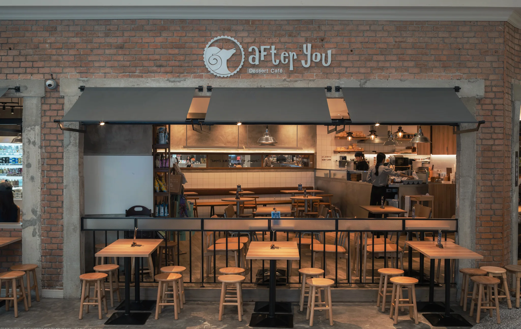 Front elevation with After You signage, dark awnings and timber tables.