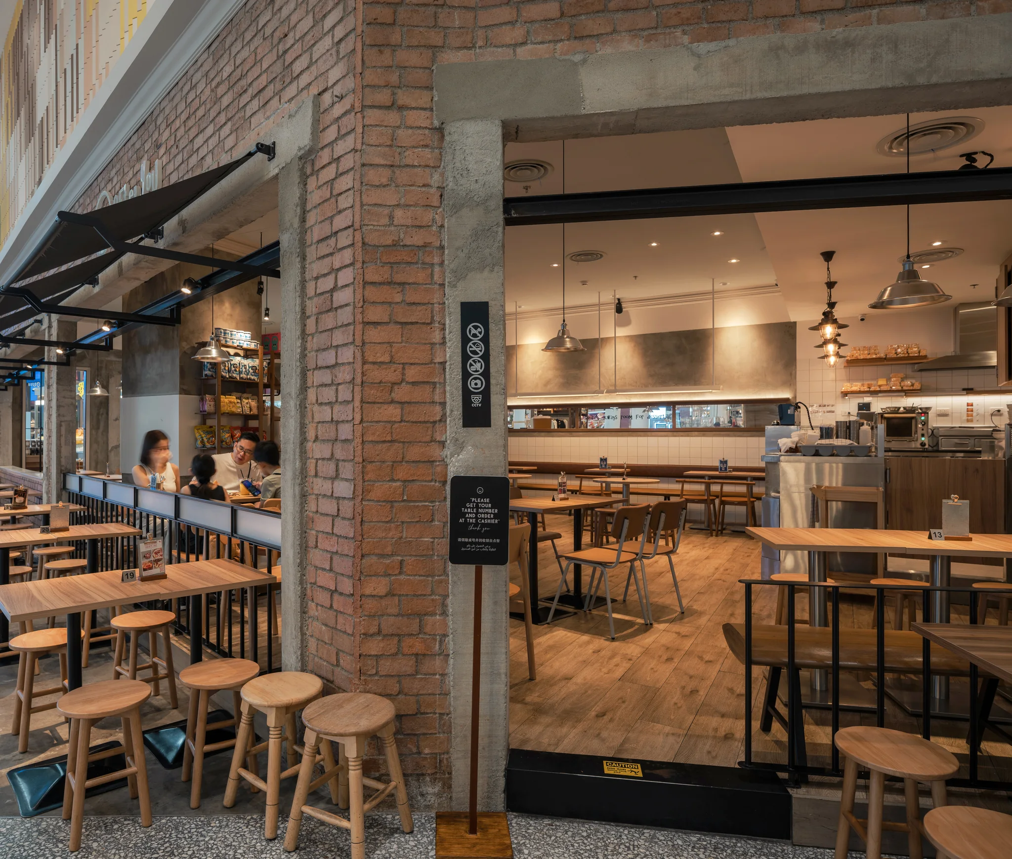 Brick pier and concrete-framed openings between edge seating and the cafe interior.