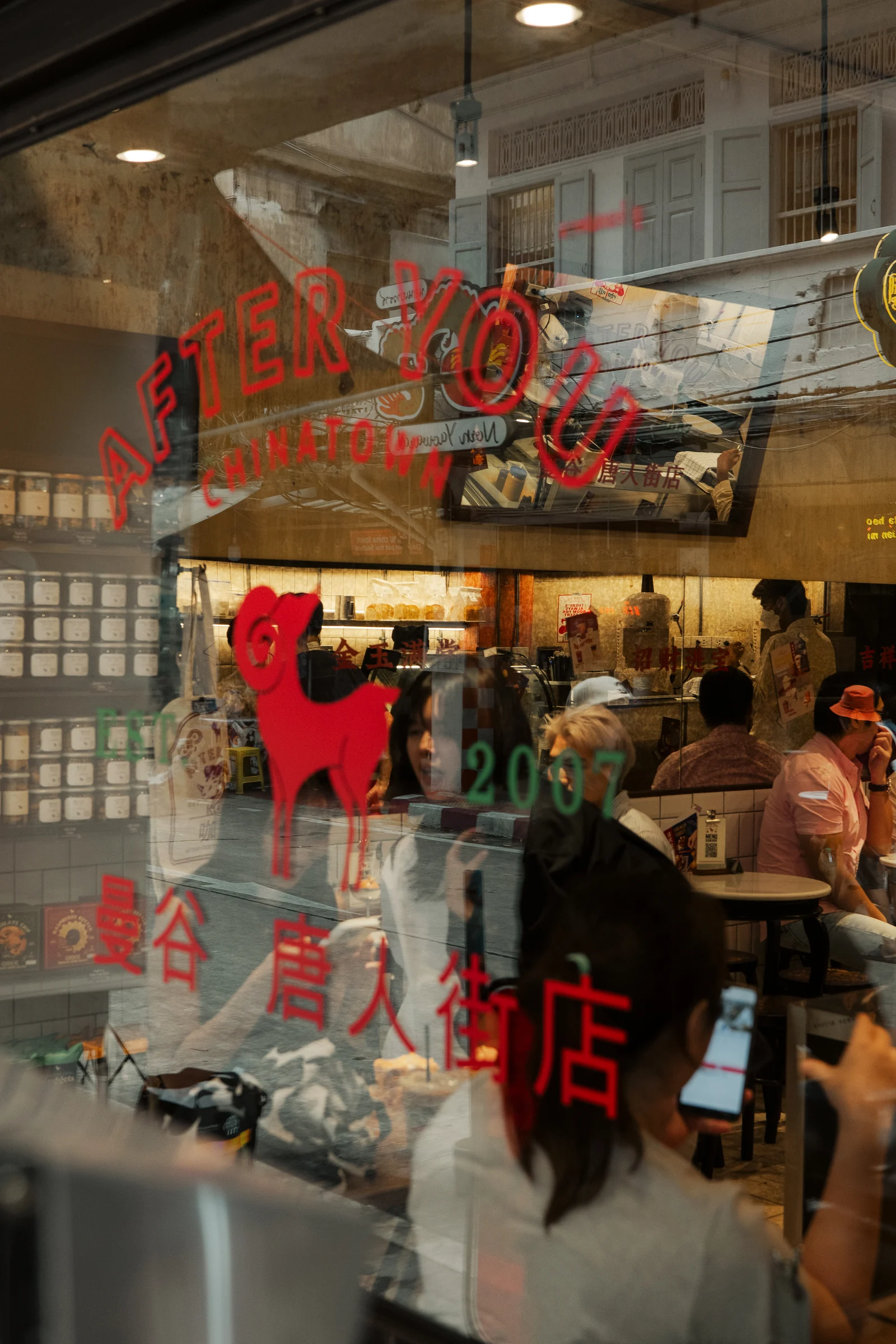 Cafe activity seen through layered storefront graphics