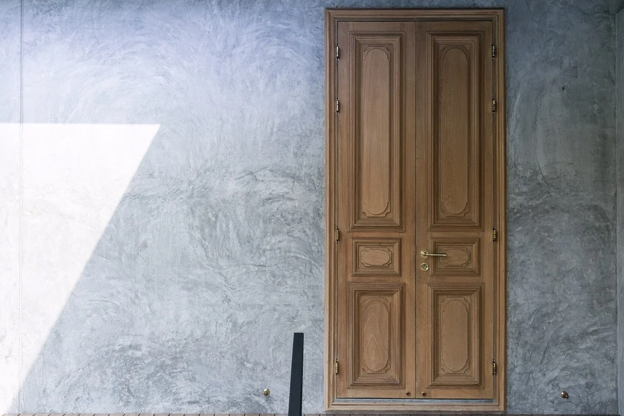 Kitisook House carved timber door against textured concrete