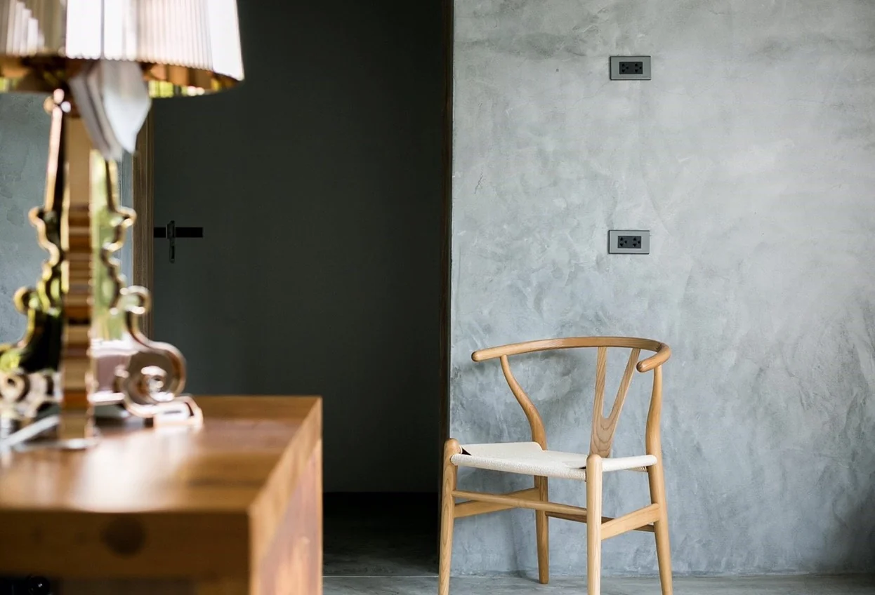 Timber chair against textured concrete at Kitisook House