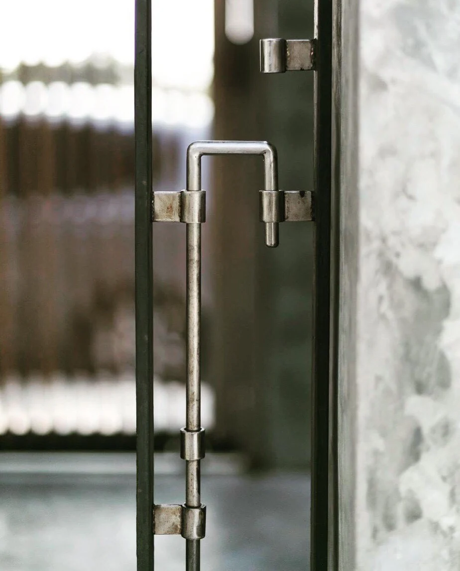 Custom metal handle on a steel-framed glass panel