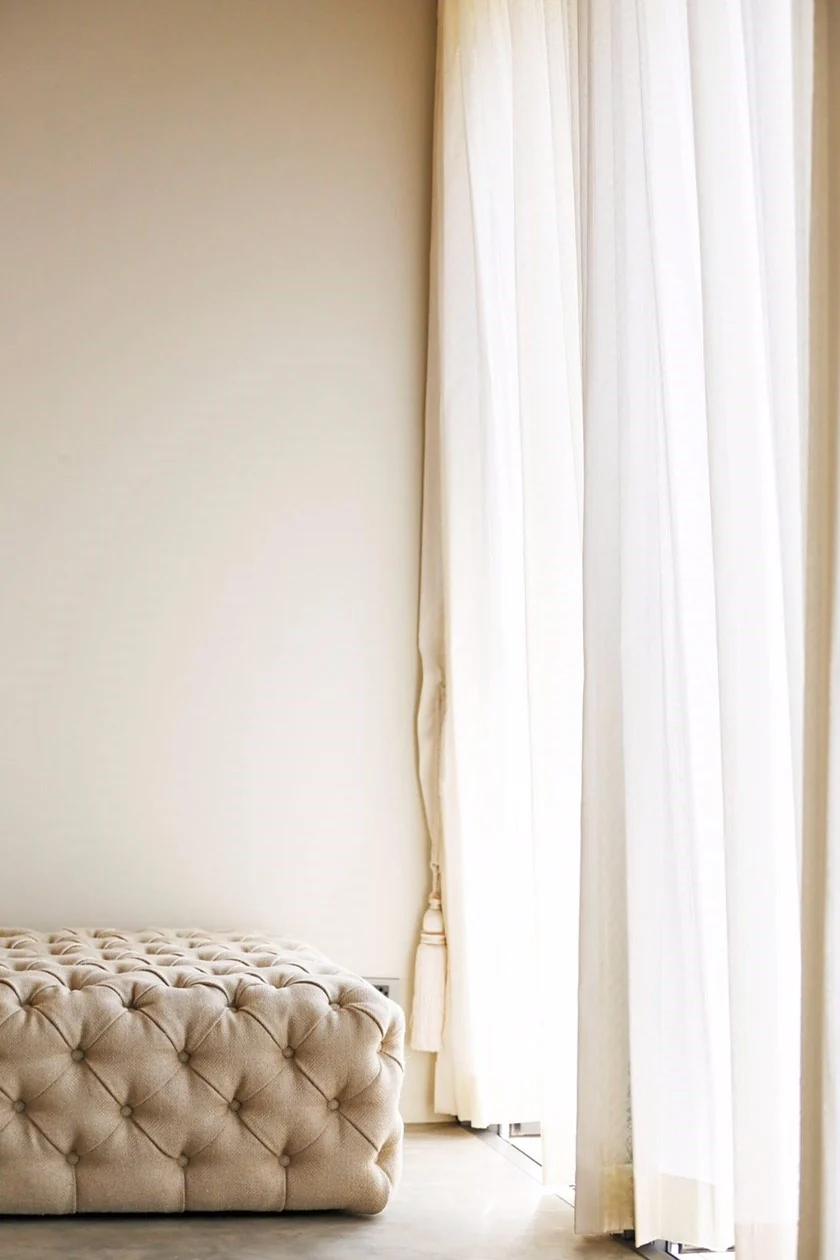 White curtain and upholstered furniture in the Kitisook House bedroom