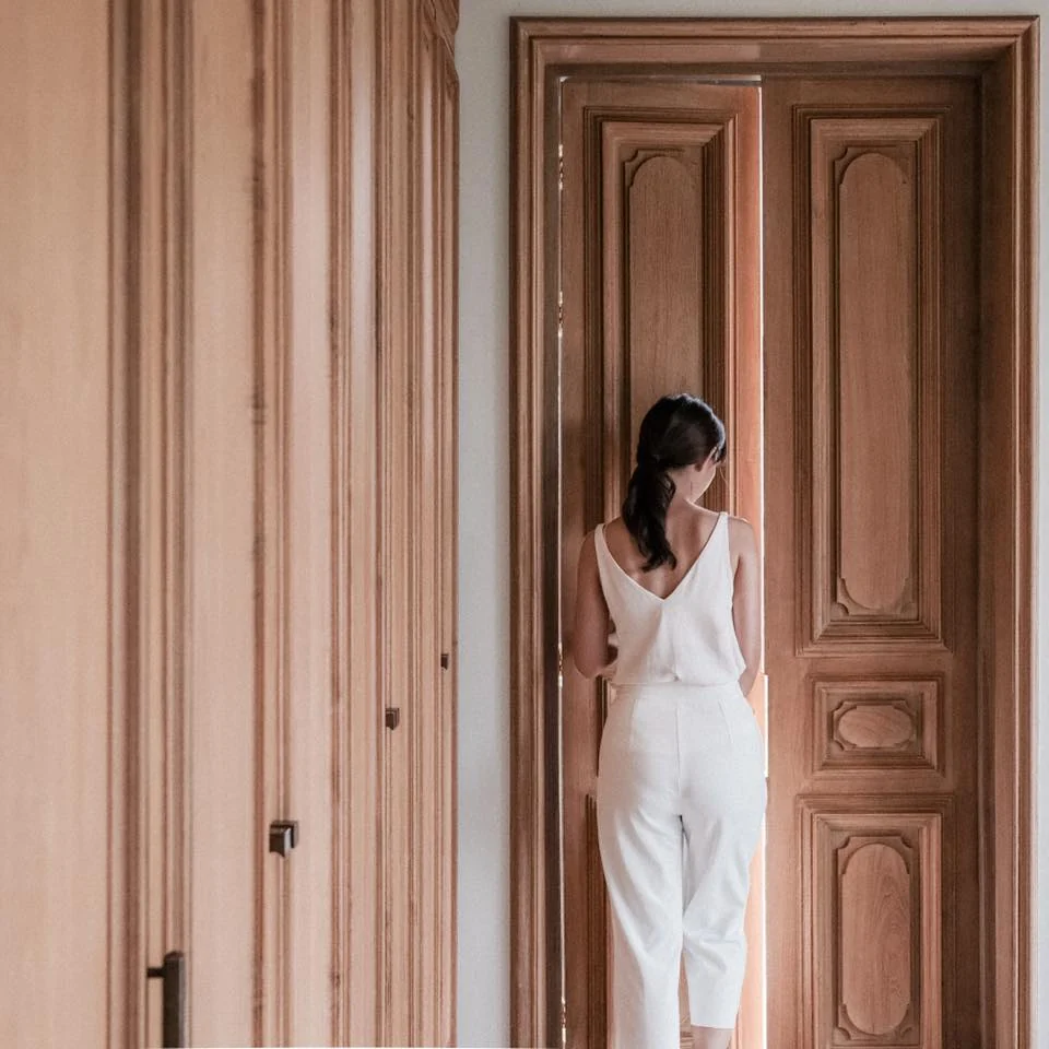 Resident passing through a carved timber doorway at Kitisook House