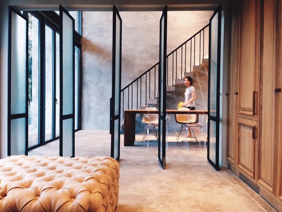Inhabited interior view through folding glass doors toward the dining room and stair