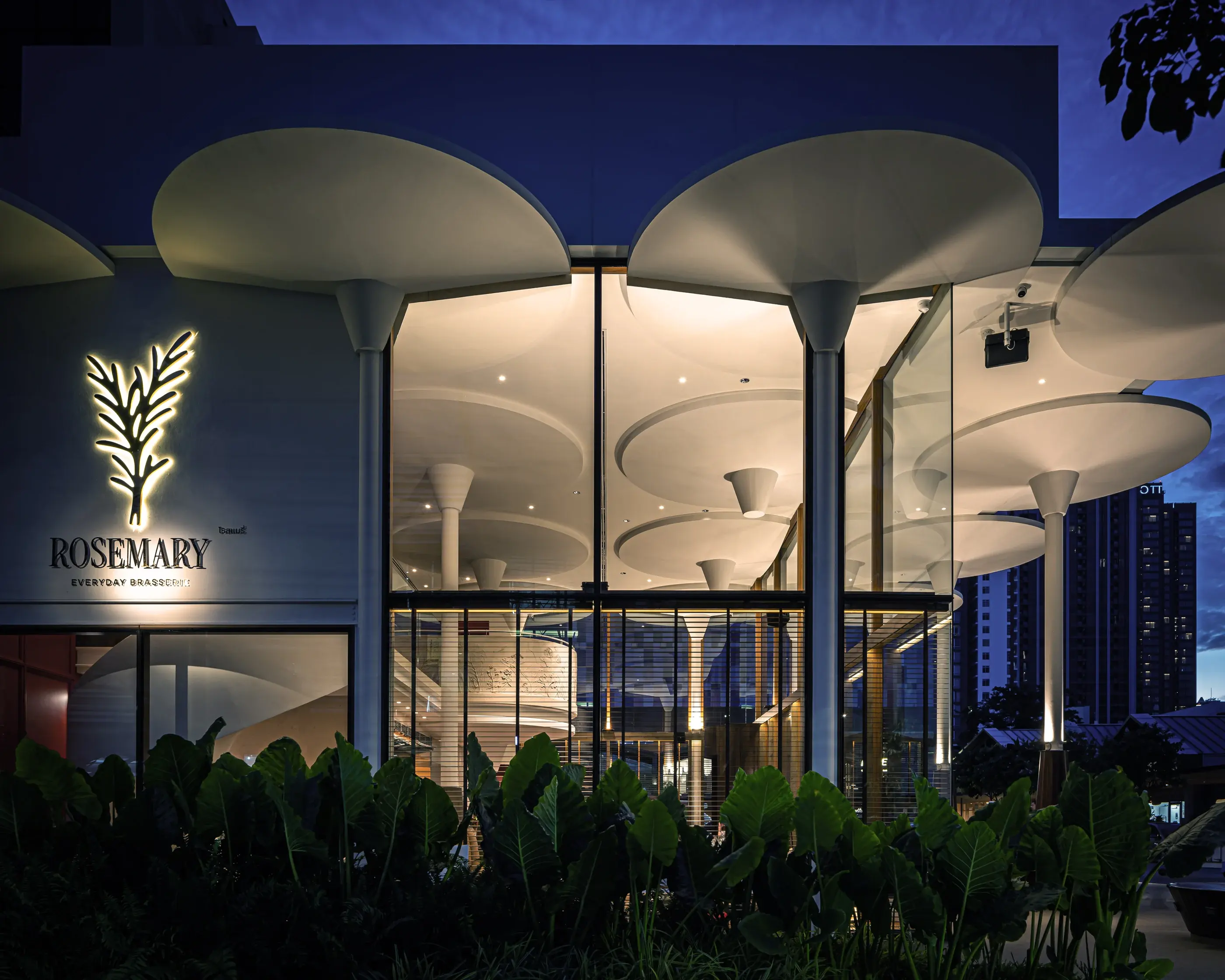 Dusk facade detail showing Rosemary signage and illuminated circular ceiling forms