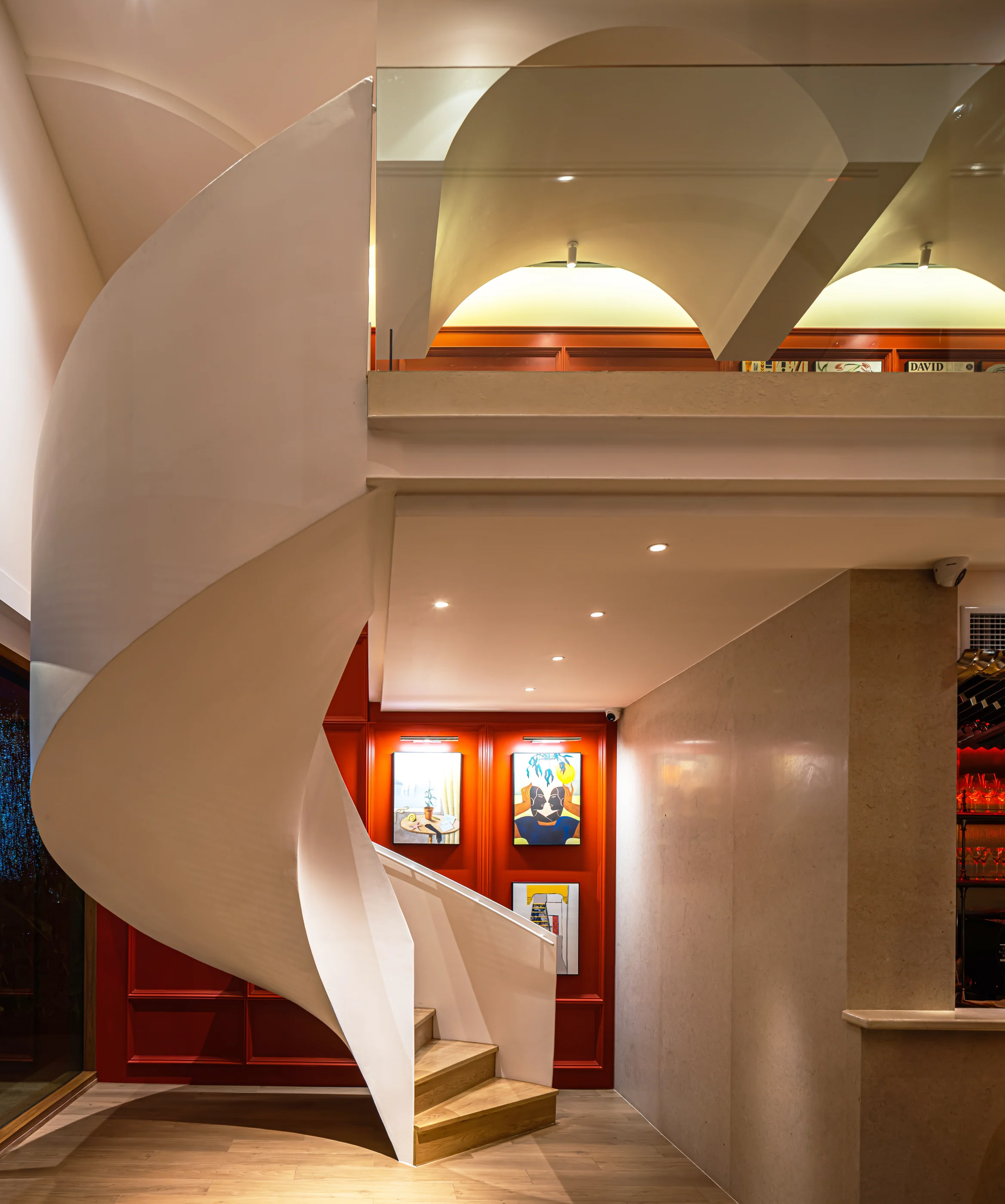 Sculptural spiral stair against the red art wall inside Rosemary Everyday Brasserie