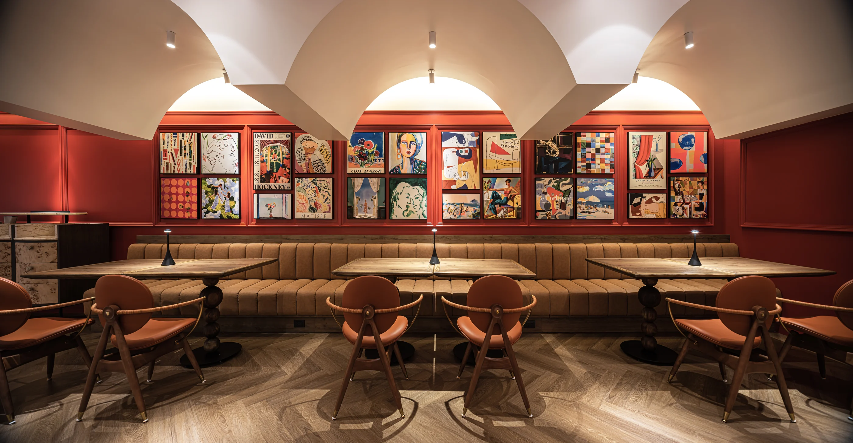Long dining banquette beneath a salon-style art wall and sculptural ceiling