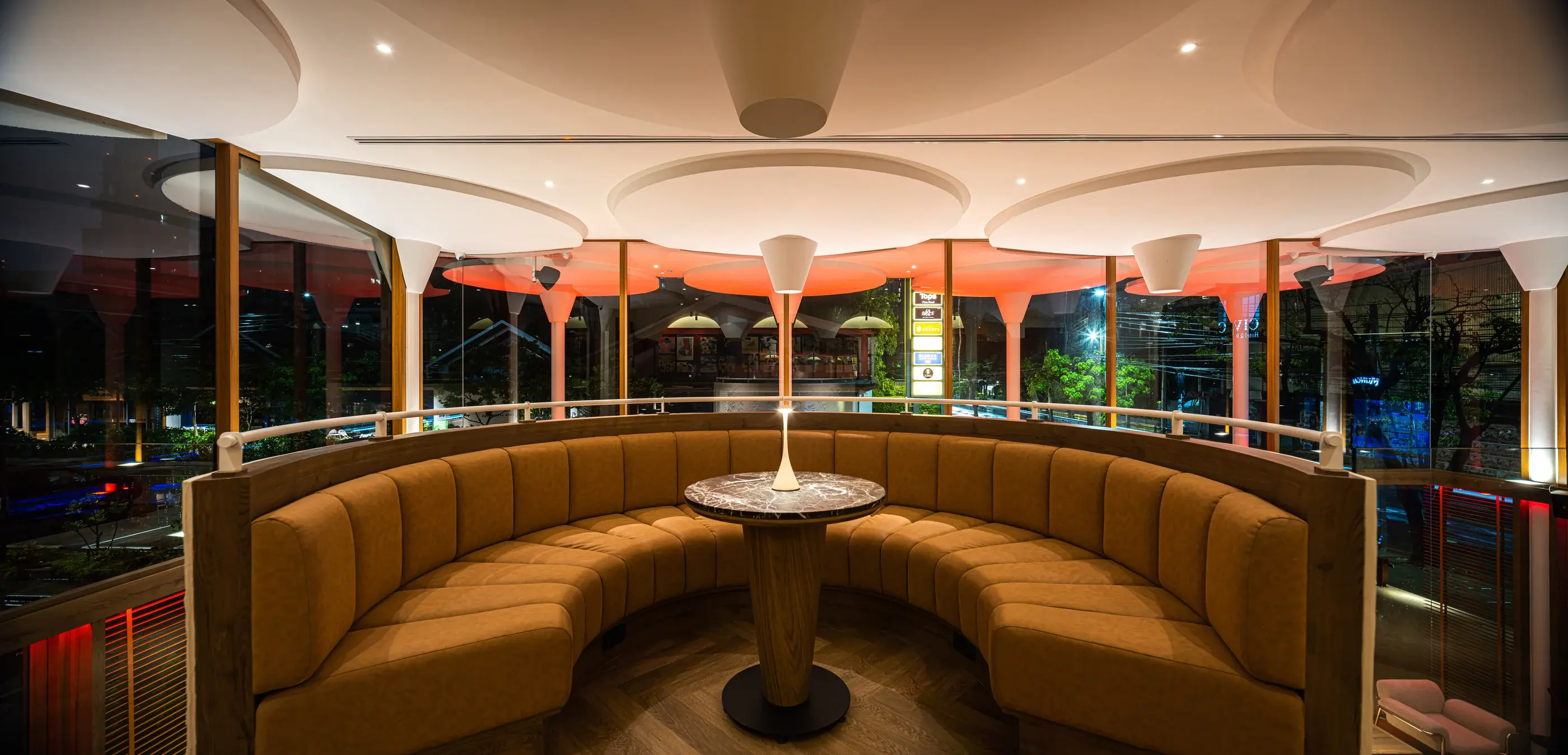 Upper-level curved banquette overlooking the street through full-height glazing