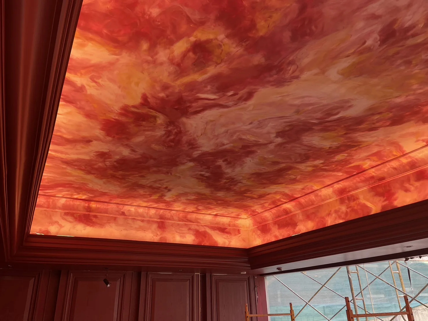 Completed custom-painted Game Room ceiling with layered red, coral and orange colour at The Club