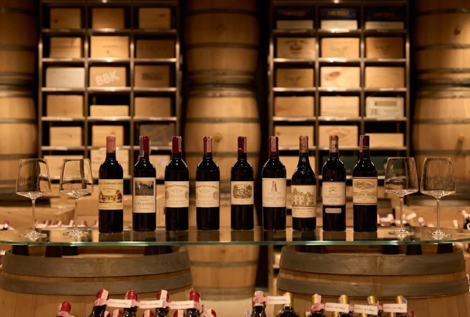 Wine bottles displayed on glass above oak barrels at Wine Gallery Bangkok