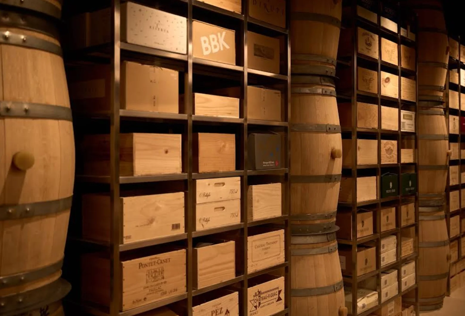 Close view of wine crates and oak barrels integrated into metal shelving at Wine Gallery Bangkok